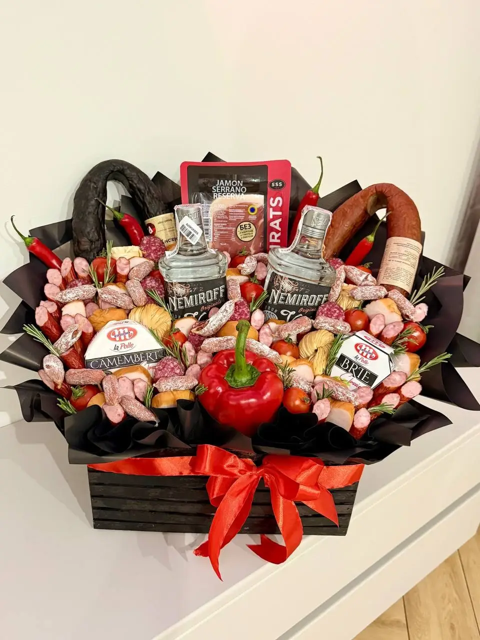 Чорна коробка з пляшками горілки, ковбасками, перцем і снеками